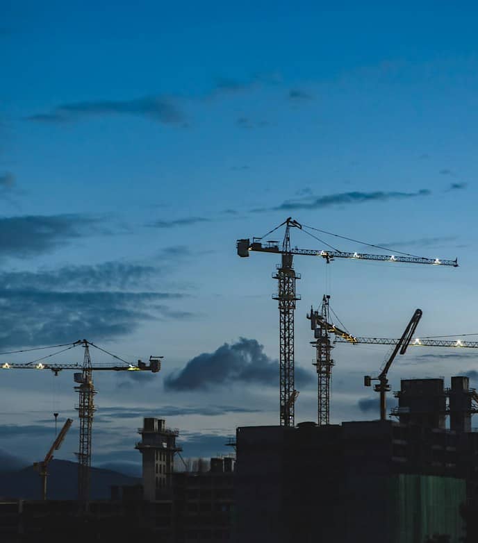 Οικοδομικοί γερανοί σε εργοτάξιο κατά το σούρουπο
