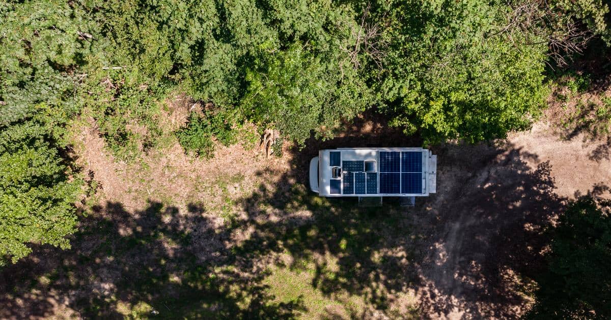 Αεροφωτογραφία ενός camper van με ηλιακά πάνελ οροφής σταθμευμένου σε ξέφωτο δάσους