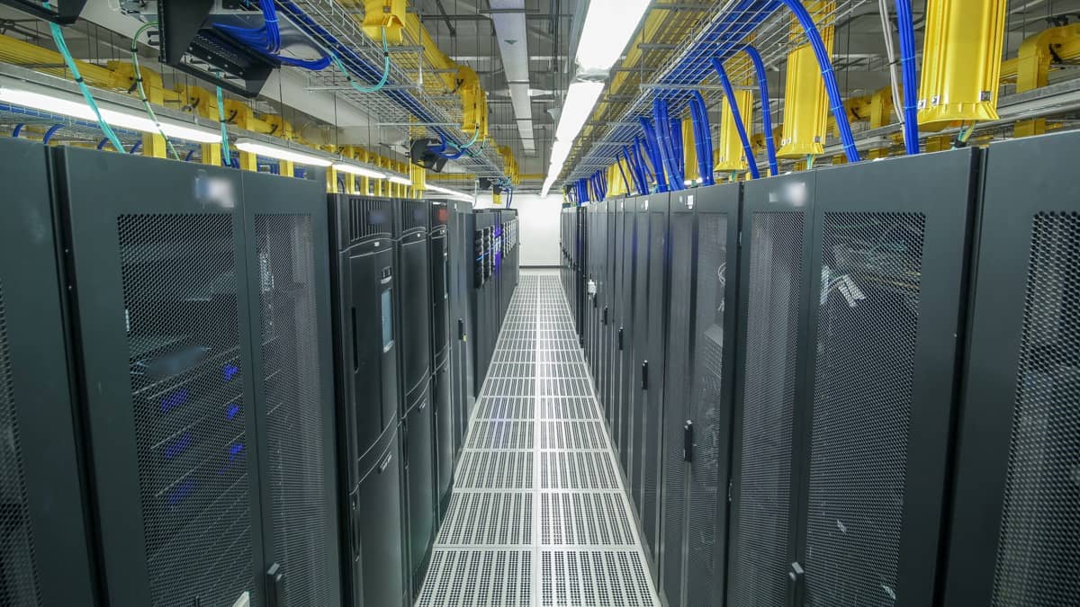 Σειρές από ικριώματα διακομιστών (server racks) σε διάδρομο κέντρου δεδομένων